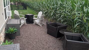 A patio area with Adirondack chairs, a table, and a black wicker planter.