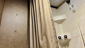 Banheiro com chuveiro, ventilador de teto e claraboia.