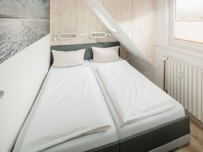 A bedroom with a bed, a window, and a radiator. - Holiday Apartment With 1 Bedroom (Norderney)