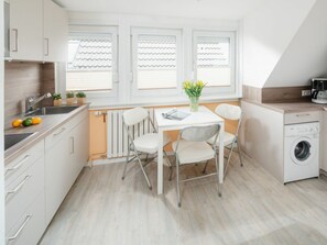 Una cocina moderna con una mesa de comedor, sillas, una lavadora y un radiador.