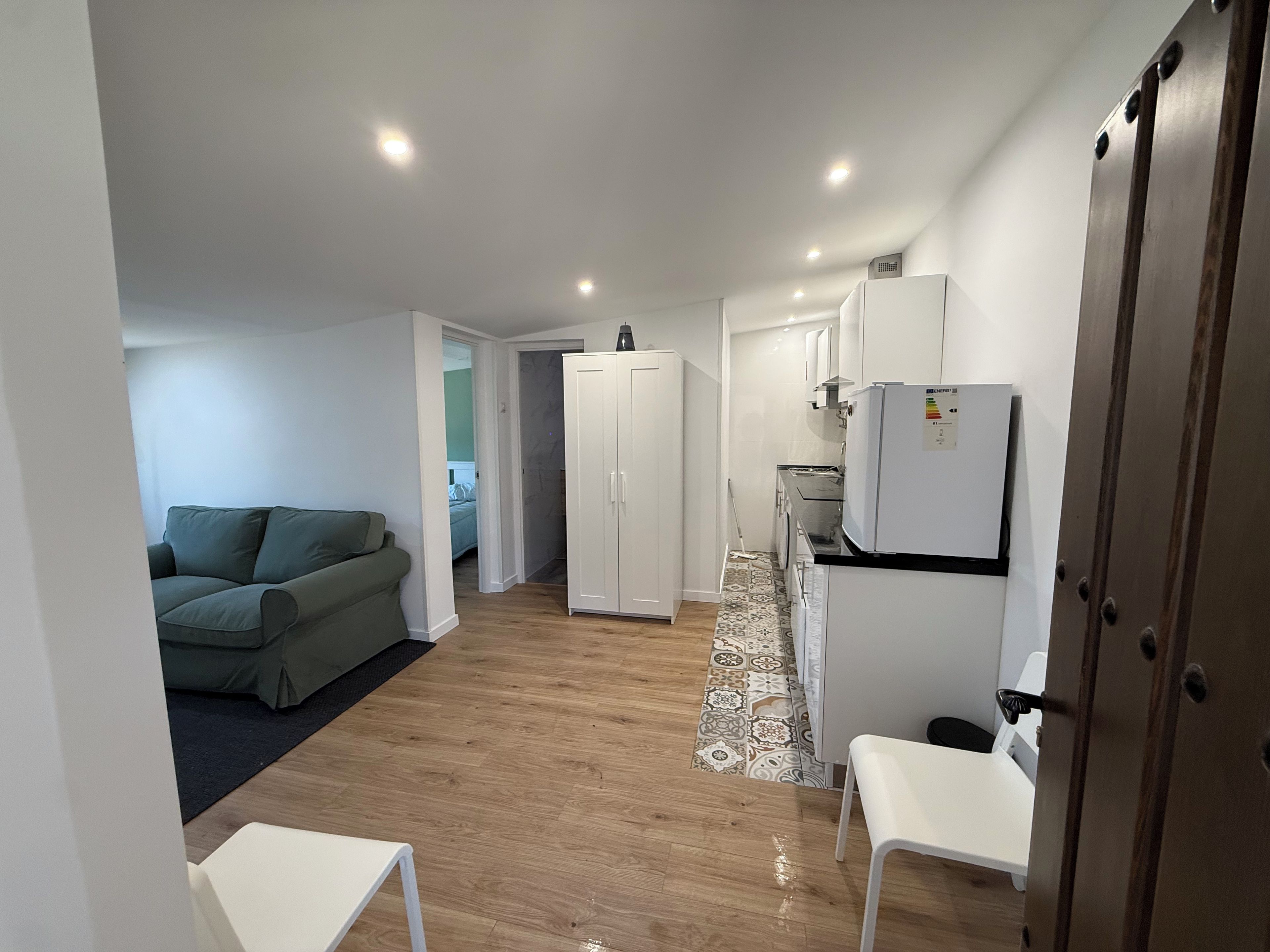 Un espace de vie compact comprenant un coin cuisine, un canapé, une table à manger et une armoire.