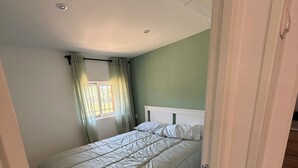 A bedroom with a bed, a window with curtains, and a door leading to another room. - Cozy 1-bedroom apartment in lovely Ambite with beutiful views (Ambite)