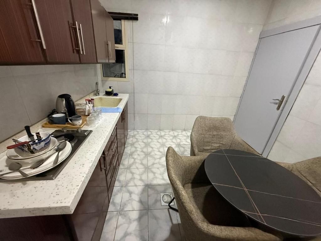 Cozinha compacta com bancada, pia e um pequeno espaço de refeições com mesa e cadeira.