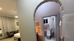 Habitación de hotel con cama, escritorio y baño con inodoro y lavamanos.