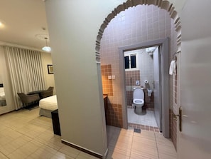 Ein Hotelzimmer mit Bett, Schreibtisch und einem Badezimmer inklusive Toilette und Waschbecken.