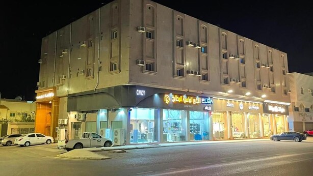 Un edificio de varios pisos con locales comerciales en la planta baja, incluyendo una tienda de dulces y un muebleria.