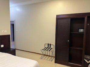 A hotel room with a bed, a wardrobe, a chair, and a door.