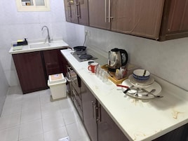 Una cocina pequeña con lavamanos, estufa y armarios.