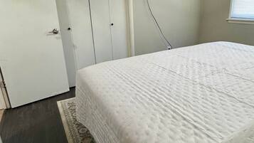 Una camera da letto con un letto, un armadio, una televisione a parete e una finestra con persiane.