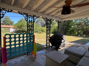 Un patio cubierto con una parrilla, asientos al aire libre y una cerca decorativa.