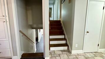 A staircase leading to a second floor with a dark wooden floor and a light-colored tiled floor on the landing.