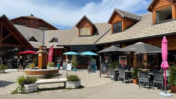 Een binnenplaats met buitenmeubilair, houten gebouwen en een fontein.