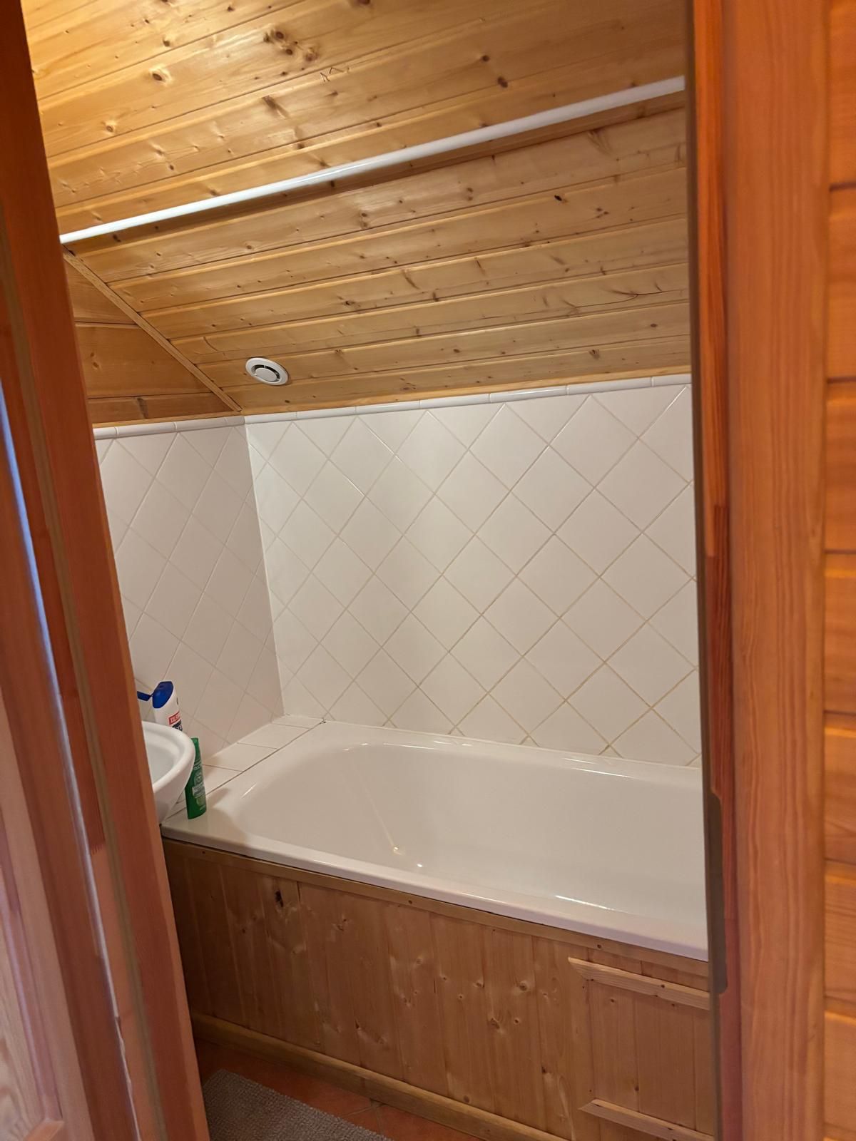A wooden-paneled bathroom with a white bathtub, a sink, and a toilet.