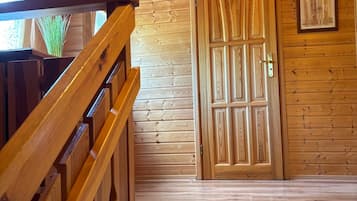 Un intérieur en bois avec un escalier, une porte en bois et un tableau encadré au mur.