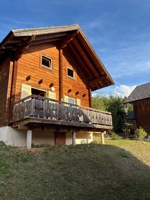 A wooden chalet with a balcony and a small attached structure.