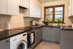 Cocina compacta con lavadora Bosch, hervidor y lavaplatos.
