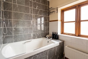 A bathroom with a freestanding bathtub, a window with wooden frames, and a towel rack.