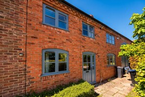 A red brick building with a small garden area, a door, and a window.