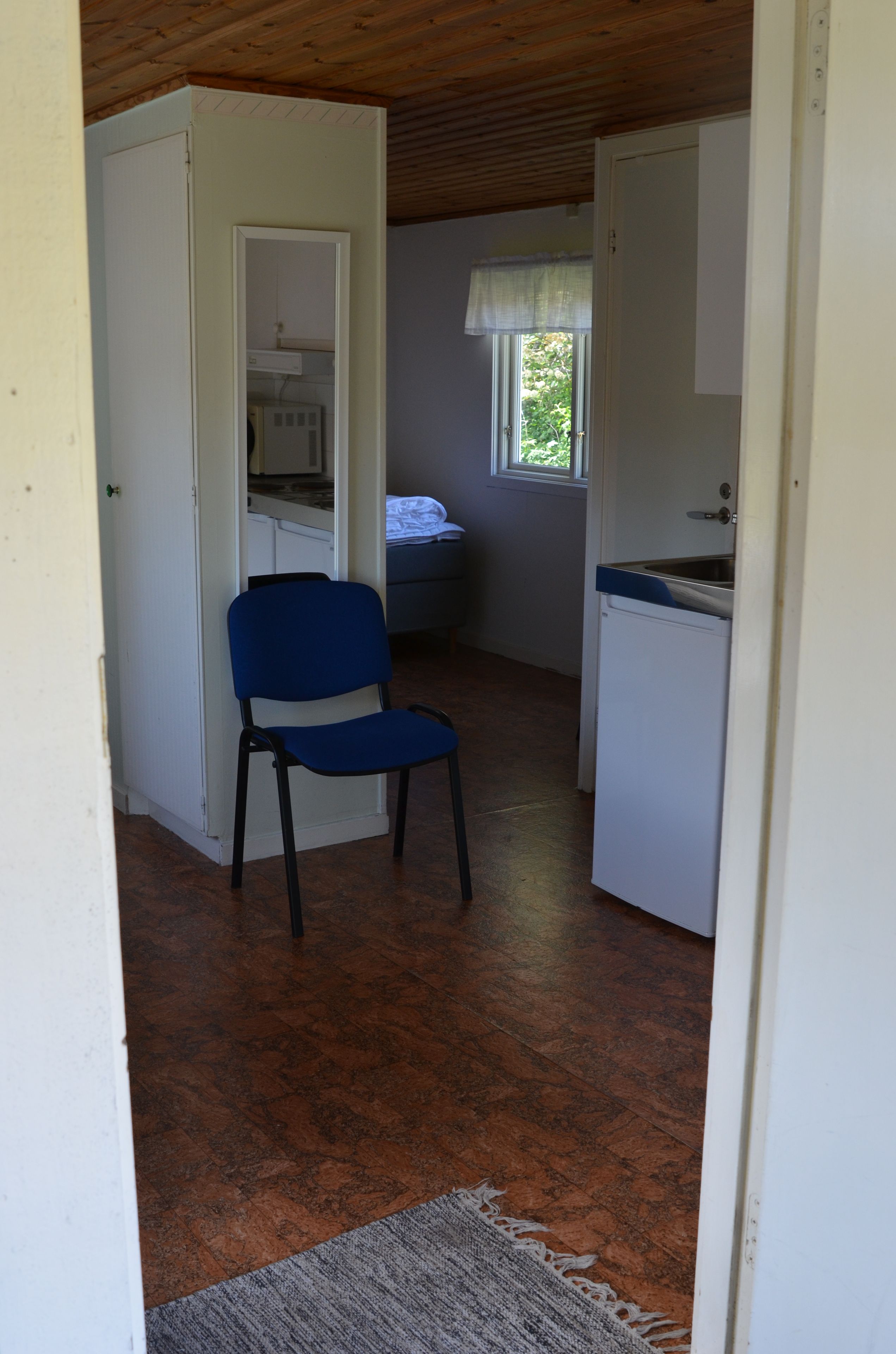 A compact room with a kitchenette, a chair, and a window.