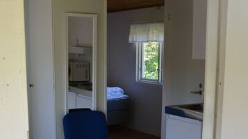 A compact room with a kitchenette, a chair, and a window.