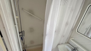 A bathroom with a shower, a sink, and a toilet. - Grönhögens Stugby (Degerhamn)