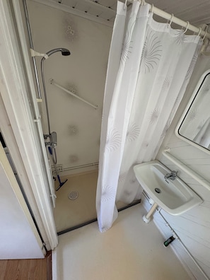 A bathroom with a shower, a sink, and a toilet. - Grönhögens Stugby (Degerhamn)