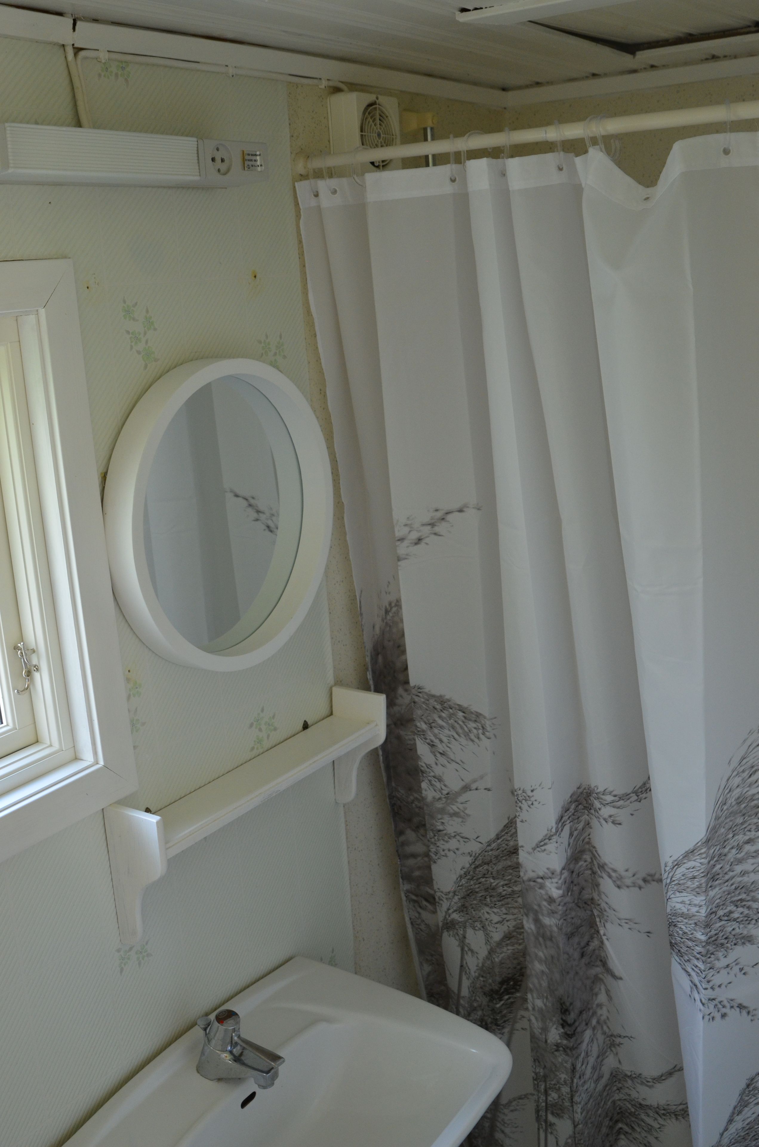 A bathroom with a white sink, a mirror, and a shower curtain with a tree pattern.