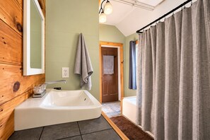Une salle de bain avec une baignoire, un lavabo, un miroir et un rideau de douche.