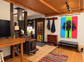 Un salon chaleureux avec une cheminée, des meubles en bois, un téléviseur et des œuvres d’art aux couleurs vives.