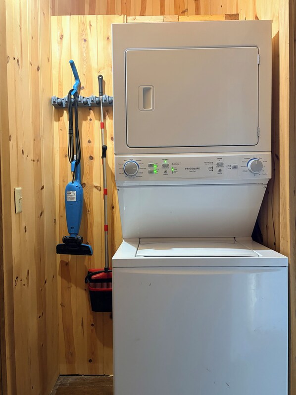 A laundry room with a washing machine, a vacuum cleaner, and a mop.