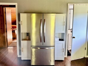 A stainless steel refrigerator with two doors, white cabinetry, and a wooden floor.