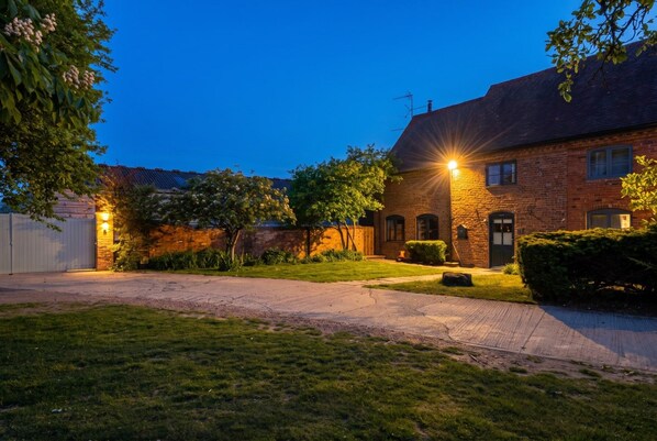 A brick house with a well-maintained lawn and a driveway leading to a garage.