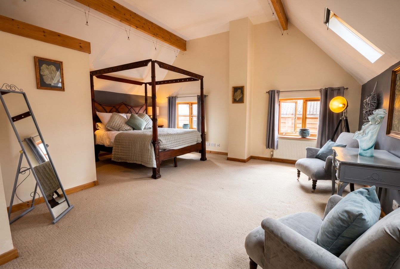 A bedroom with a four-poster bed, a desk with a chair, and a window with curtains.