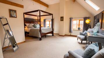 A bedroom with a four-poster bed, a desk with a chair, and a window with curtains.