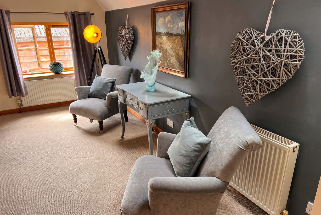 A living room with a sofa, armchair, and a table with a vase.