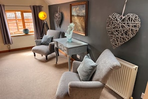 A living room with a sofa, armchair, and a table with a vase.