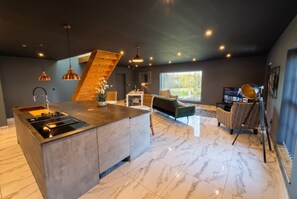 Een moderne keuken met een centraal eiland, een zithoek met een bank, en een groot raam voor natuurlijk licht.
