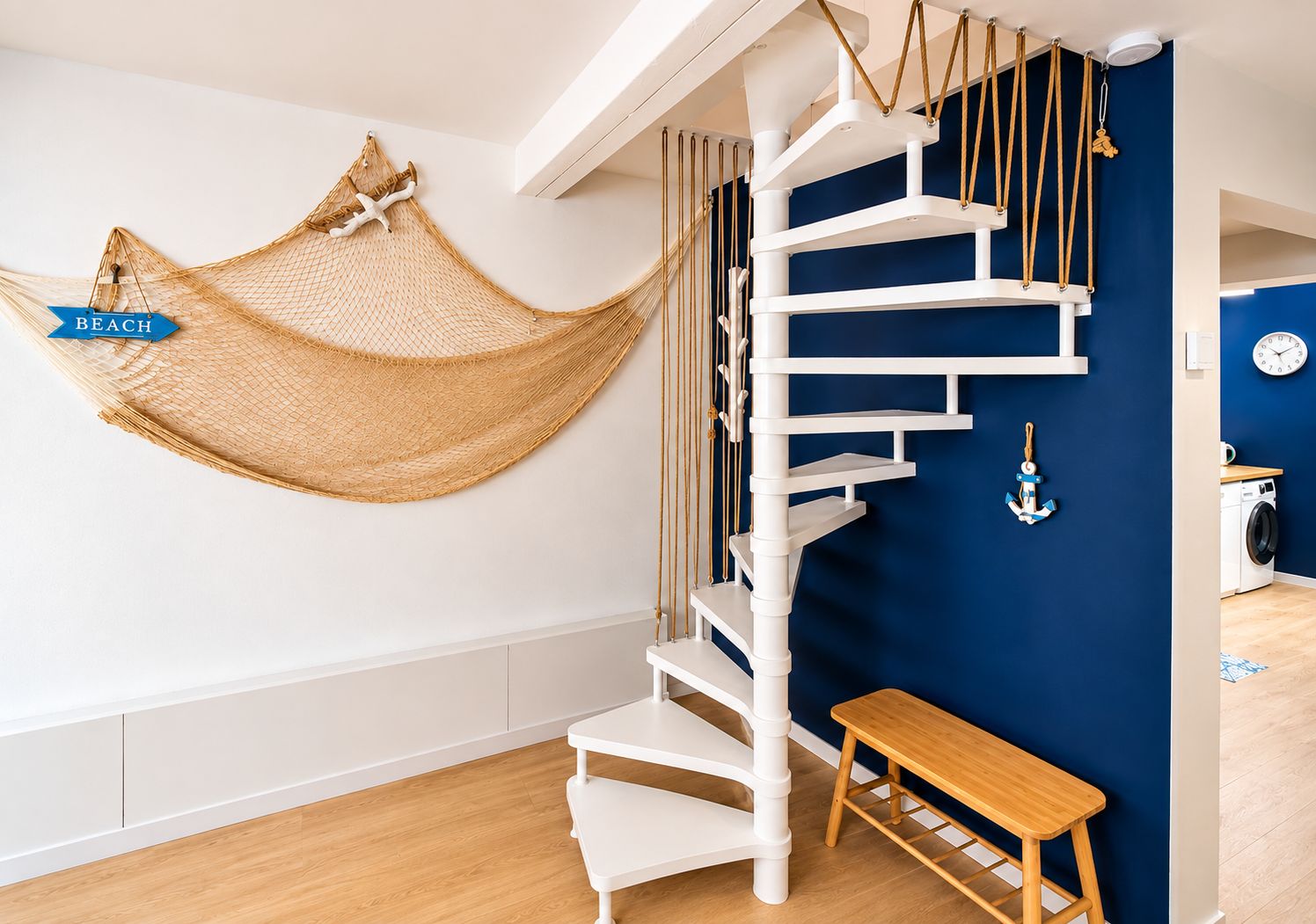 A spiral staircase with a hammock and an anchor decoration in a room with a blue accent wall.