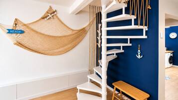 A spiral staircase with a hammock and an anchor decoration in a room with a blue accent wall.