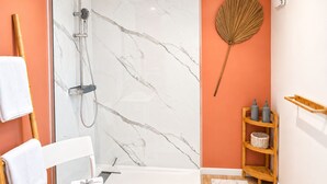 Ein Badezimmer mit Dusche, Handtuchhalter, einem Holzboden mit Pflegeprodukten und einem dekorativen Fächer.