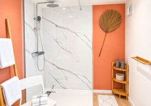 Ein Badezimmer mit Dusche, Handtuchhalter, einem Holzboden mit Pflegeprodukten und einem dekorativen Fächer.