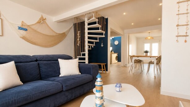 Ein modernes Wohnzimmer mit einem blauen Sofa, einem weißen Couchtisch und einem dekorativen Leuchtturm.