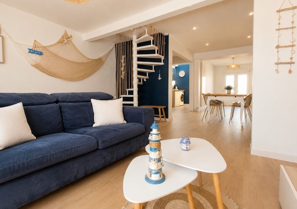 Ein modernes Wohnzimmer mit einem blauen Sofa, einem weißen Couchtisch und einem dekorativen Leuchtturm.