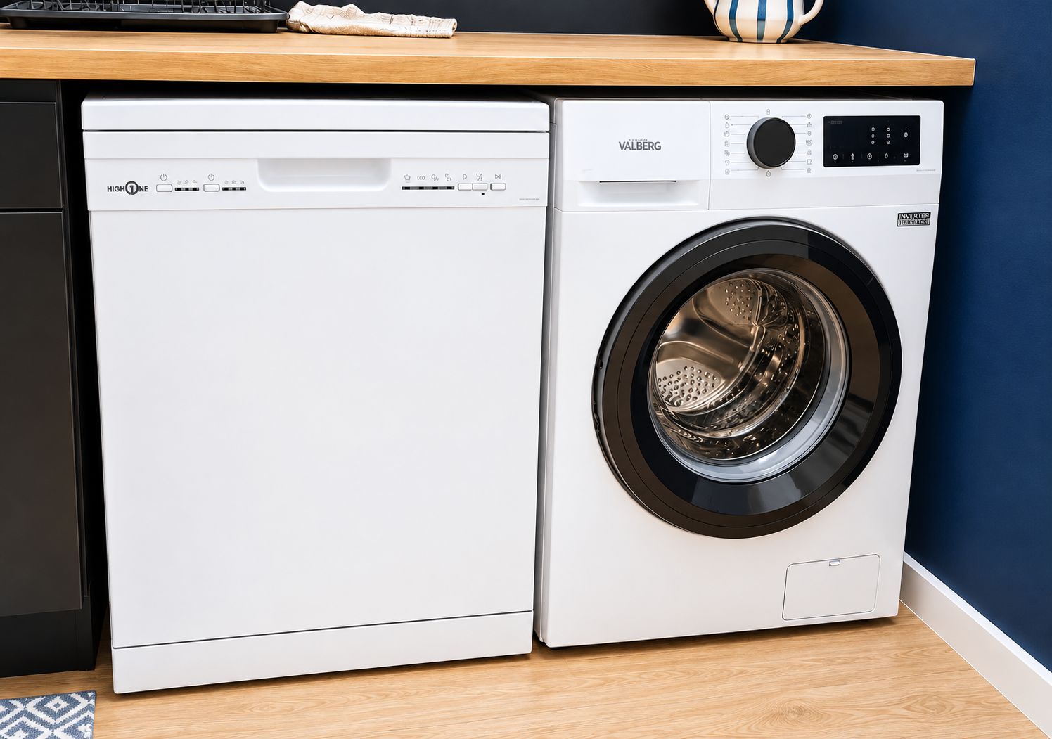 Un lave-linge et un sèche-linge à chargement frontal, dotés d’un panneau de commande, sont placés contre un mur bleu et au-dessus d’un plan de travail en bois.