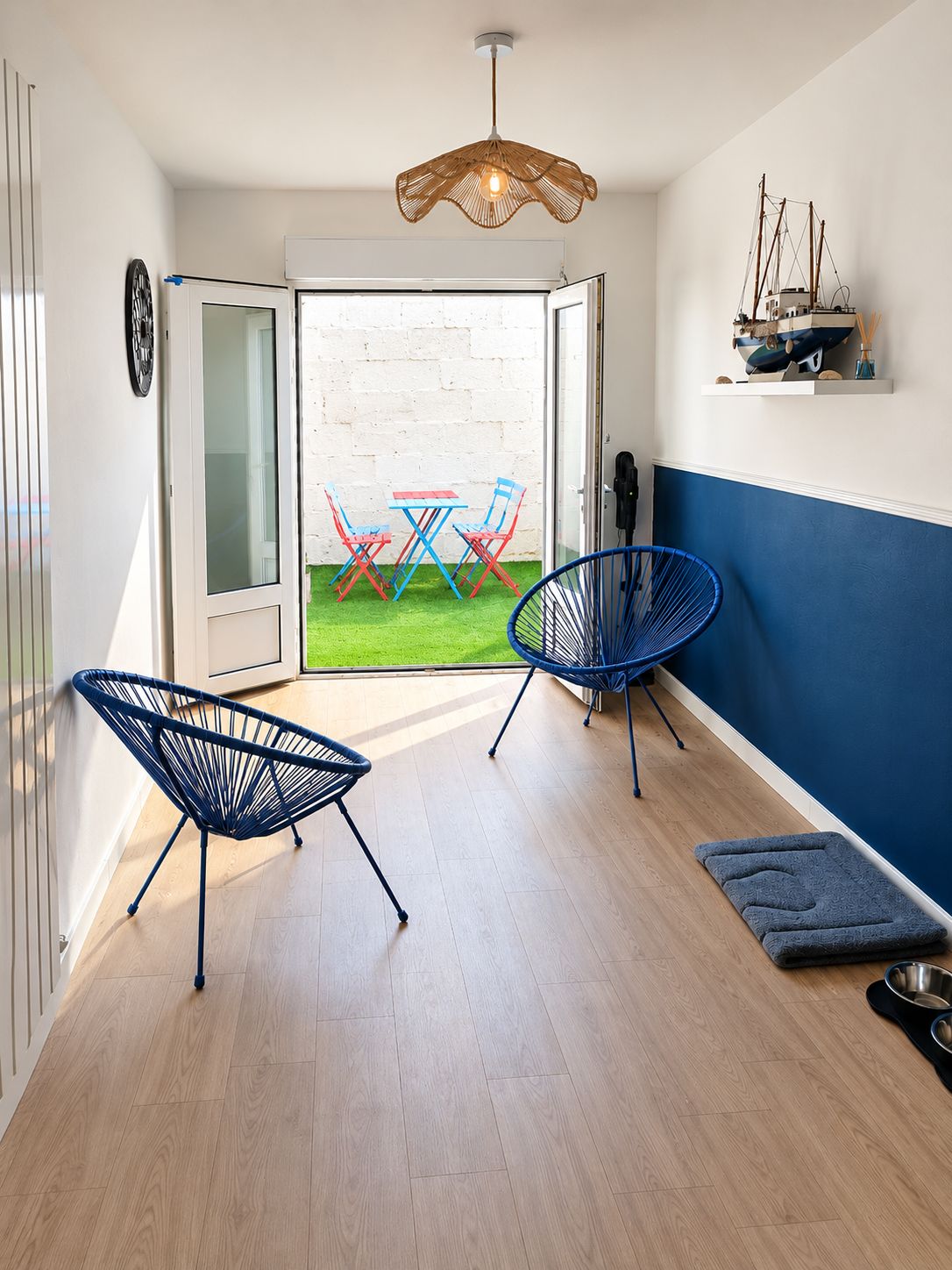 Un intérieur moderne avec un plancher en bois, une chaise bleue, une table rouge et bleue, et un luminaire suspendu.