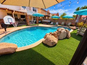 A backyard with a swimming pool, artificial grass, and a basketball hoop.