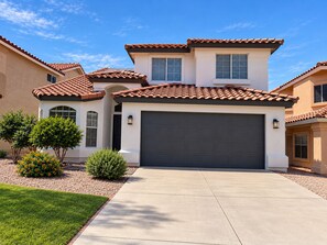 A residential house with a two-story design, a large garage, and a well-maintained front yard with landscaping.