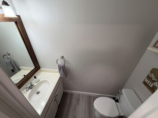 Une salle de bain équipée d’un lavabo, d’un miroir, d’un porte-serviettes et de toilettes.