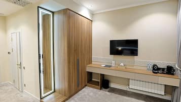 A modern bathroom with a wooden vanity, a mirror, a television, and a radiator.