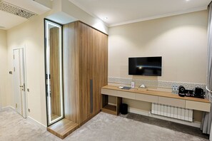 Un baño moderno con tocador de madera, espejo, televisor y radiador.
